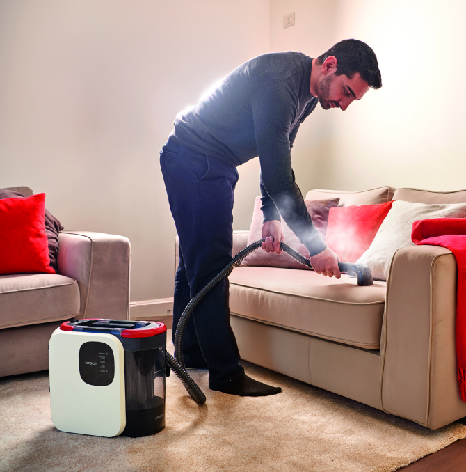 a man cleaning a sofa with a steam spot cleaner Polti