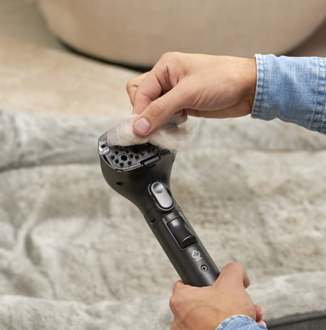 Una persona extrayendo pelo de la pistola limpiadora de manchas