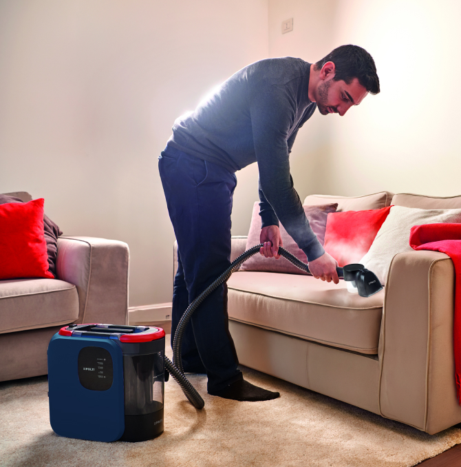 Un hombre limpiando un sofá con vapor