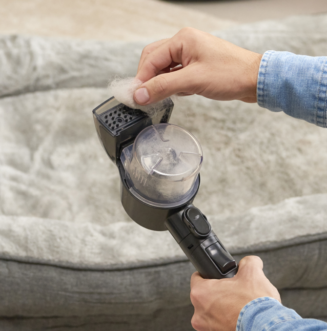 Un hombre limpiando la boquilla de un limpiador a vapor.